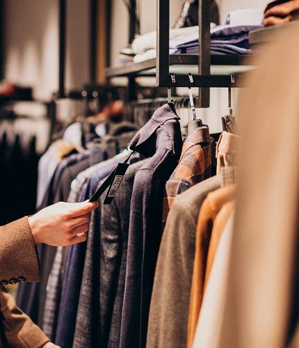 Young handsome man choosing cloth at shop